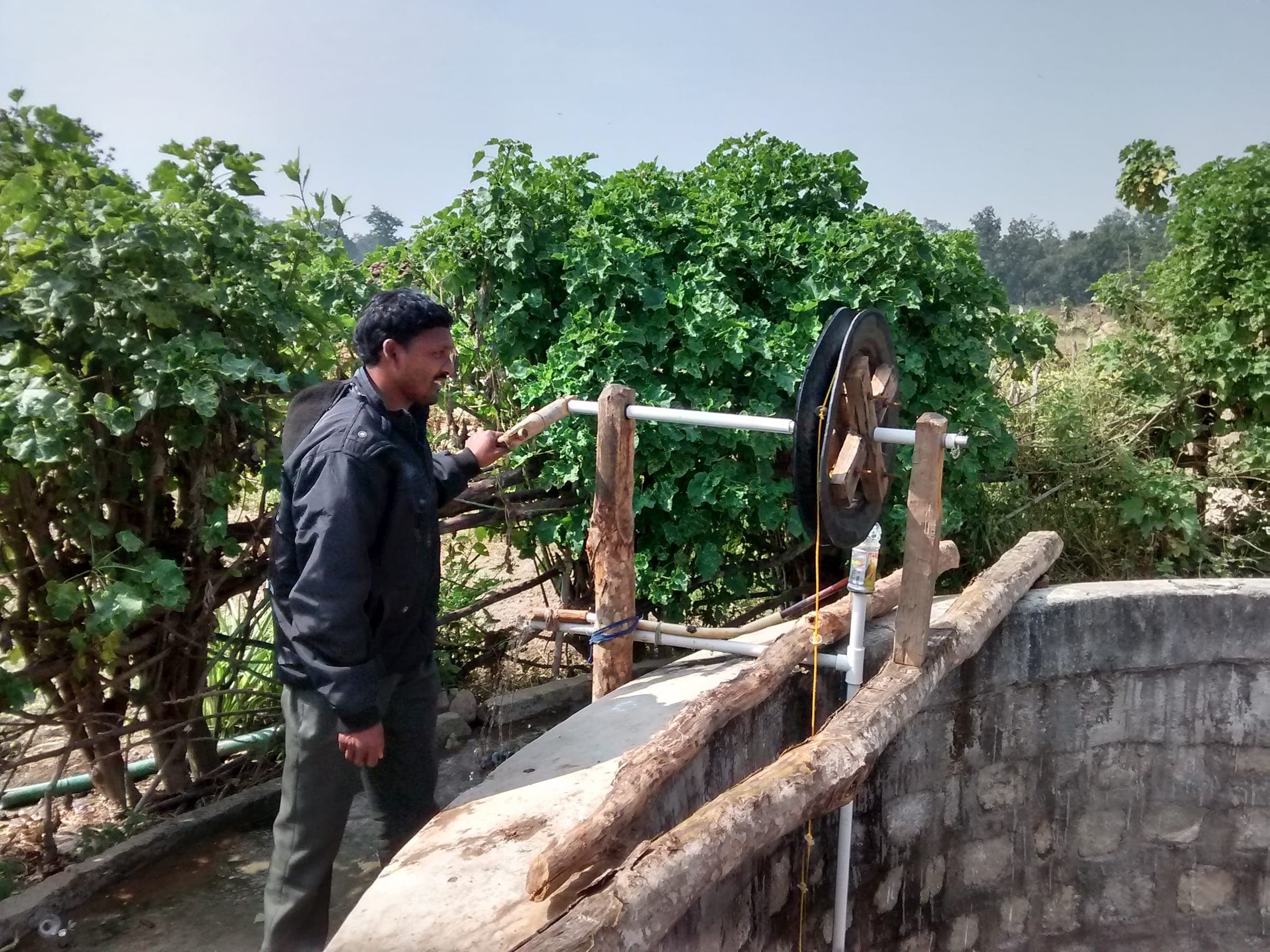 A man drawing water from a well with a wooden pulley