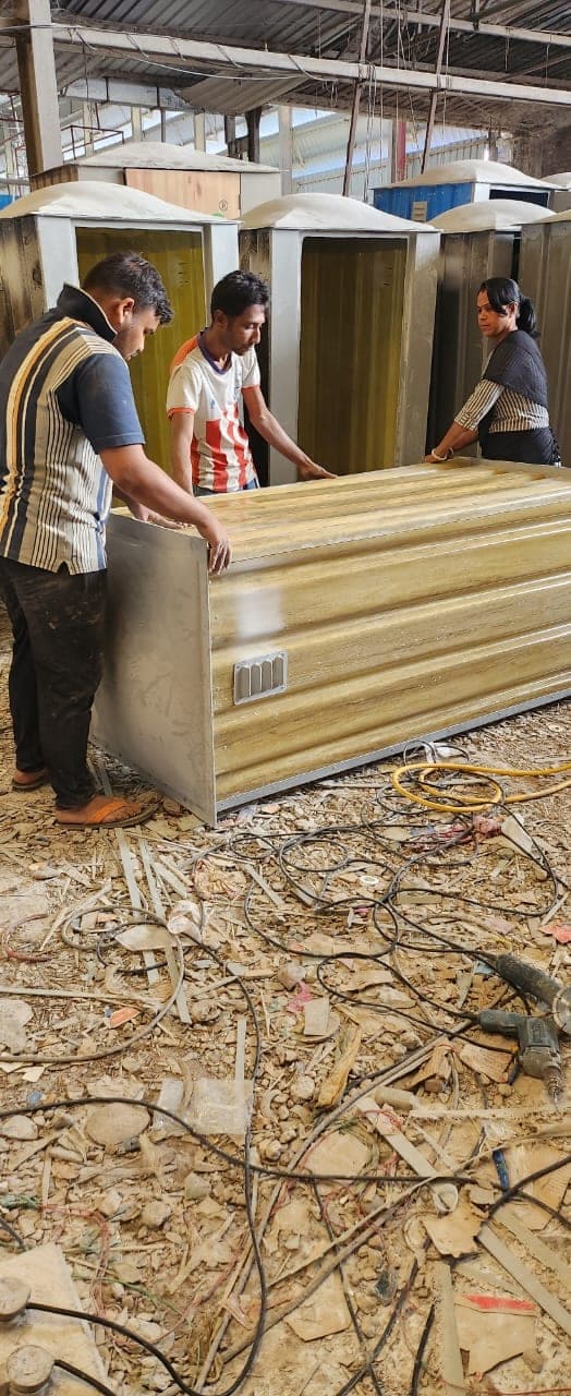 Workers assembling bio-toilet panels at the fabrication workshop