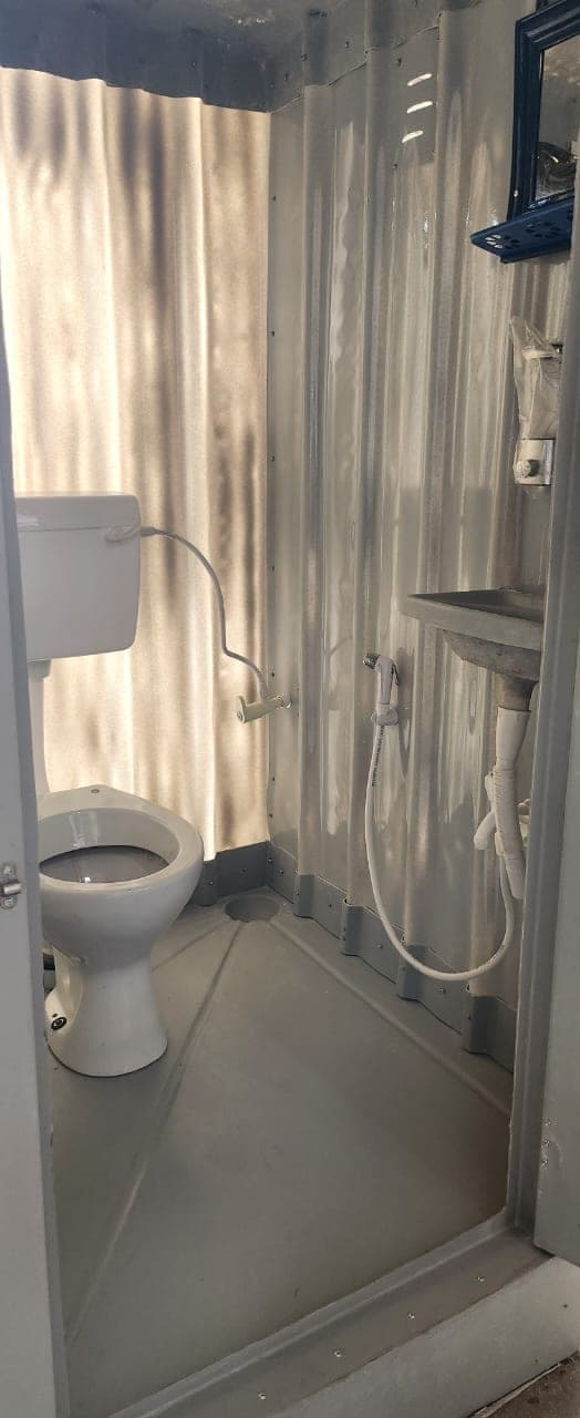 Inside a finished bio-toilet unit: a seat, handwash tap and grab rail