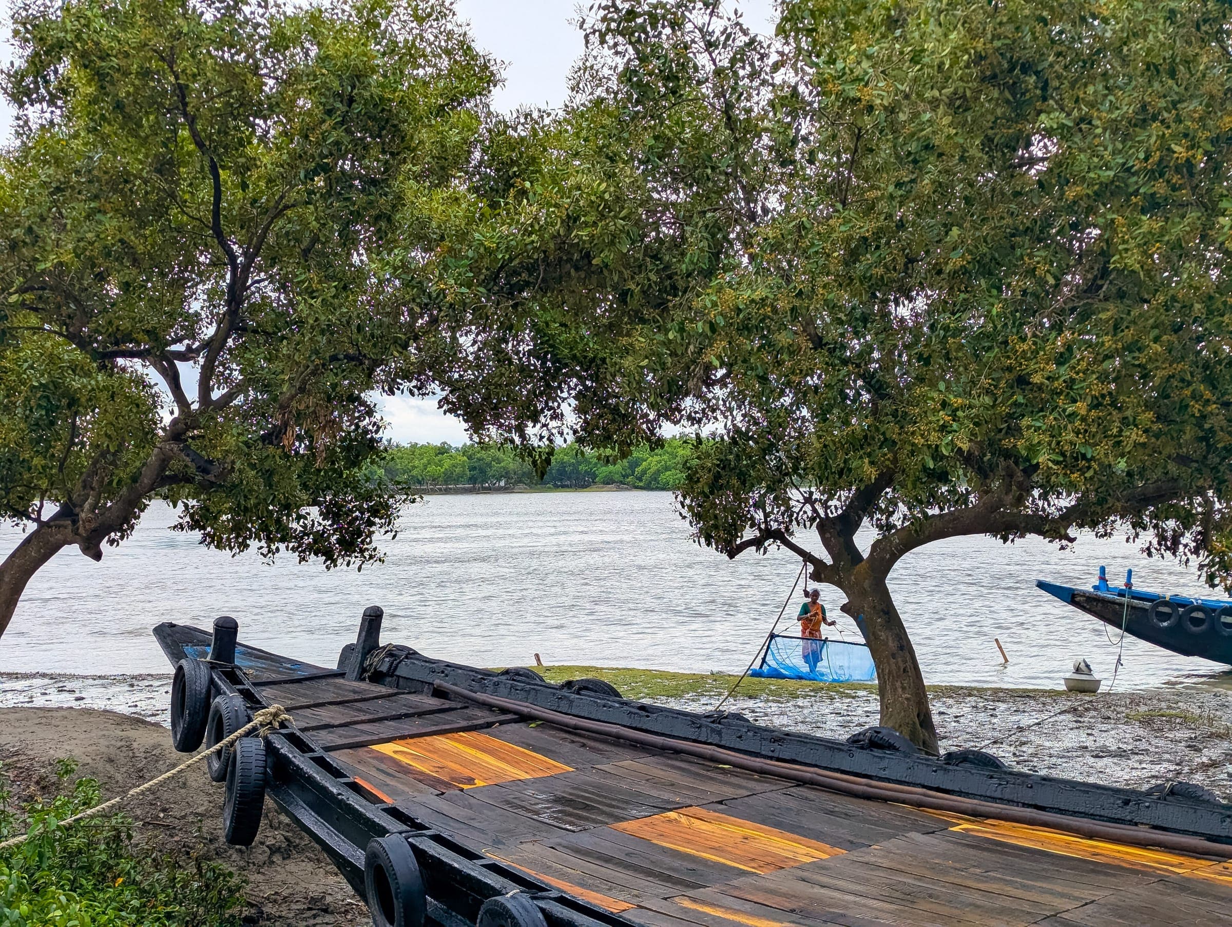 A wooden jetty reaching into a wide brackish river on the Bengal coast
