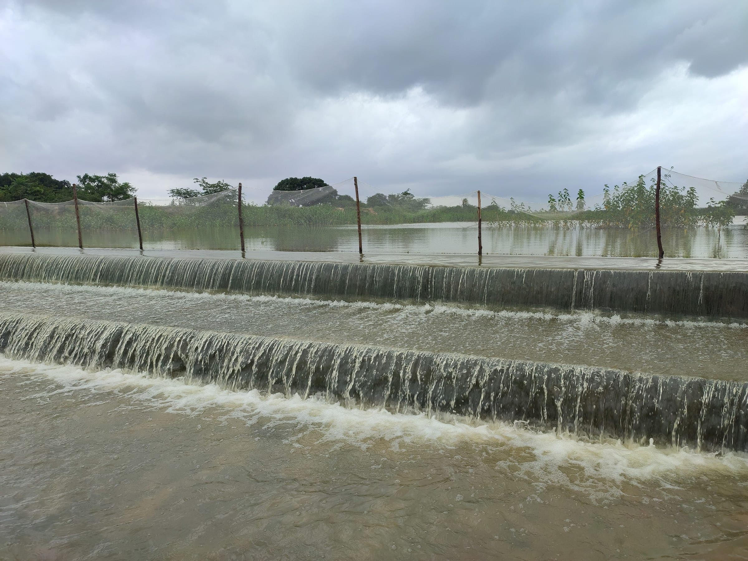 Monsoon water spilling over a stepped check dam that slows runoff so it can soak into the ground